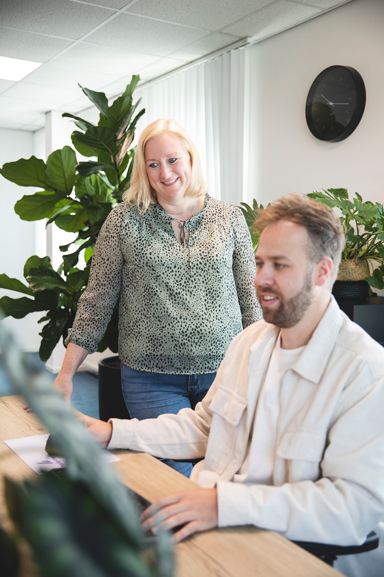 Collega's bij Marker Media overleggen samen tijdens het creatieve ontwerpproces in een groene kantooromgeving.