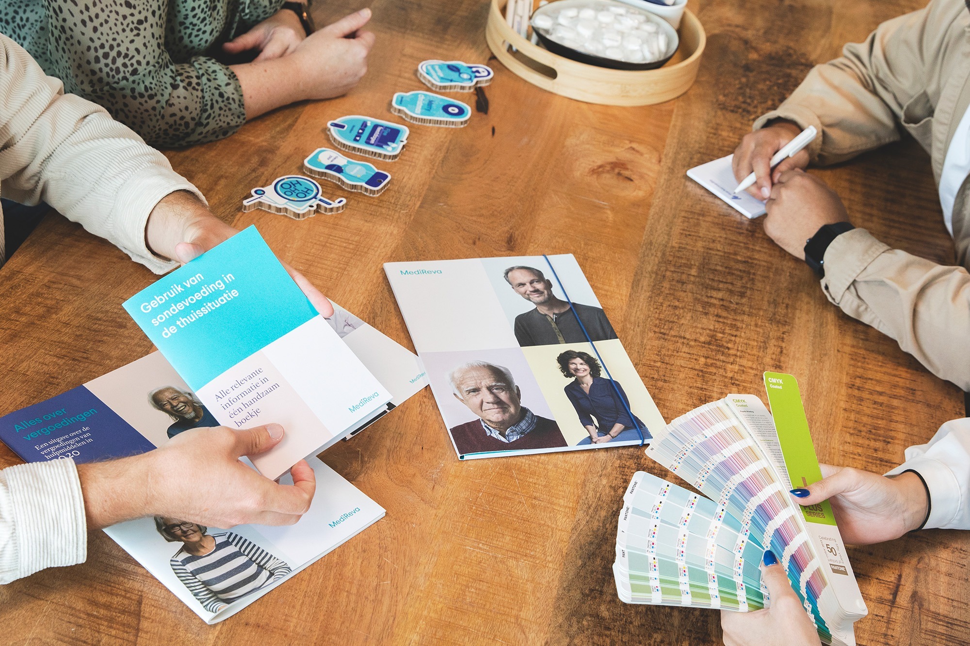 Medewerkers van Marker Media zijn in overleg. Folders en flyers net als sign materiaal liggen op tafel