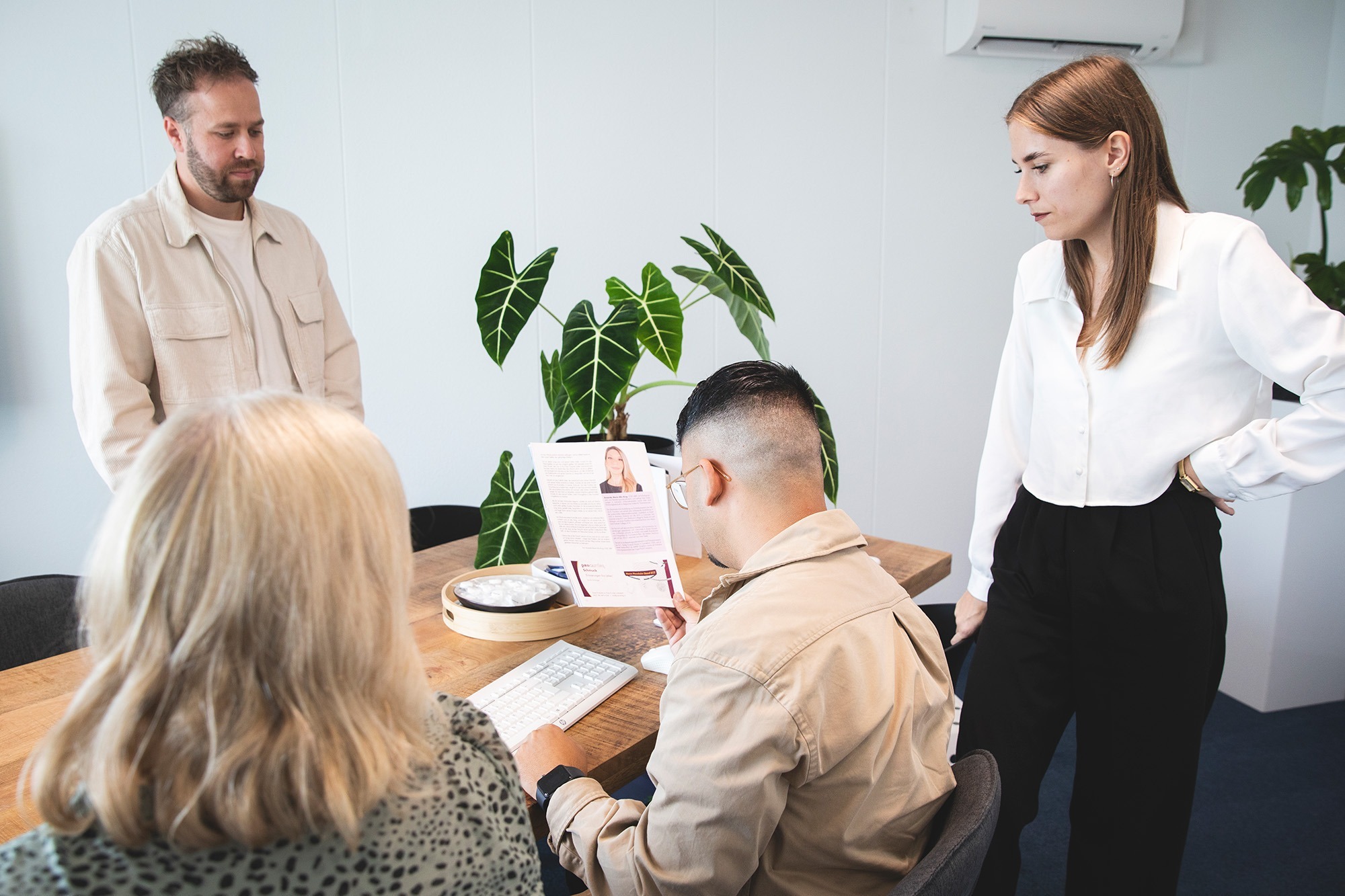 Team van Marker Media bespreekt een printontwerp tijdens een gezamenlijke vergadering in een moderne kantooromgeving.